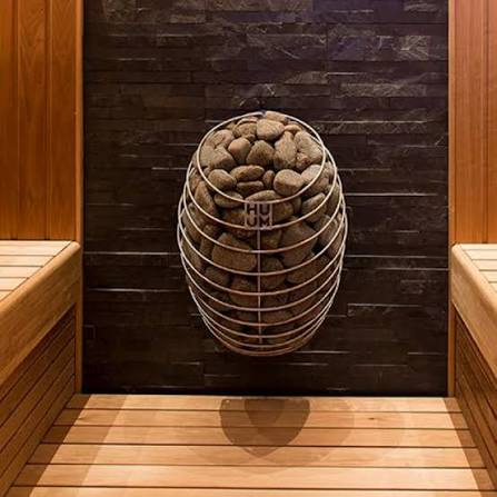 HUUM sauna heater with a sculptural stone cage and Spanish cedar benching